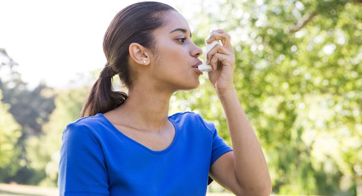 woman using an asthma inhaler