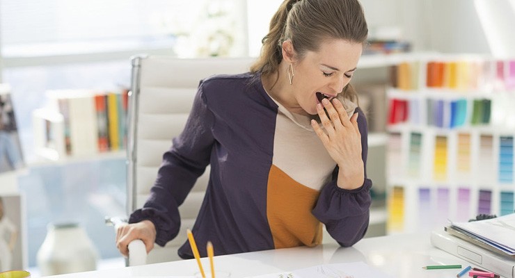 woman sitting at desk yawning