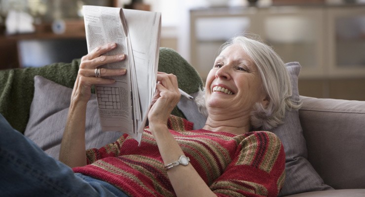 woman relaxing on couch reading the paper